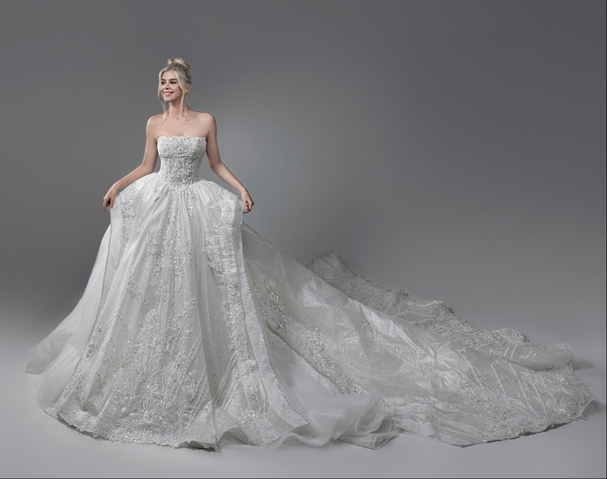 Bride wearing a Magnolia Couture princess ball gown featuring intricate lace, sparkling embellishments, and a dramatic cathedral train at Camellia Wedding Gown in Toronto.